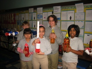 Third grade students of PS23 Mahatma Gandhi Elementary School in Jersey City, NJ posing with artwork about Antarctic biomechanics and homemade anemometers made to study wind.